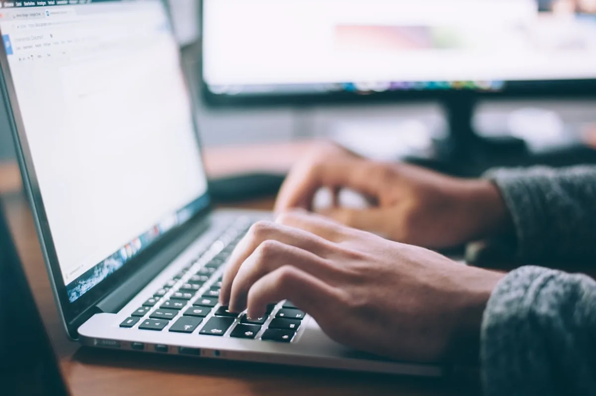 Project manager working through planning documents on a laptop at a desk