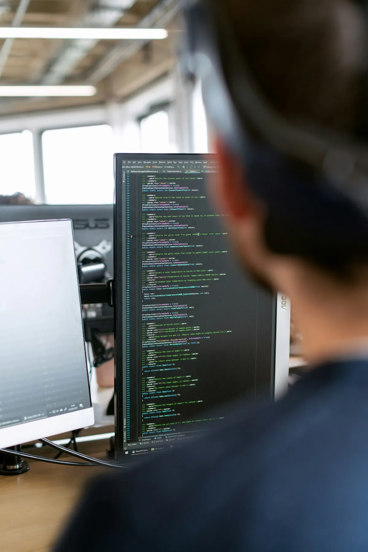 Project team member reviewing technical documentation at a workstation monitor